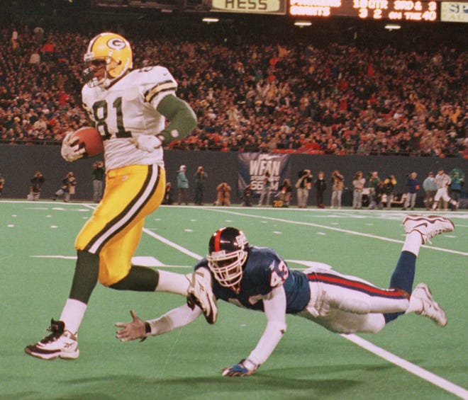 Green Bay Packers tight end Tyrone Davis eludes a diving tackle by New York Giants safety Percy Ellsworth while scoring on a 60-yard pass reception from Brett Favre during the second quarter of their game on November 15, 1998 at Giants Stadium in East Rutherford, N.J.