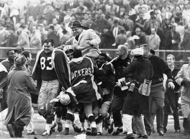The Green Bay Packers celebrate their second straight Western Division title with a 20-17 victory over the New York Giants at Milwaukee County Stadium on December 3, 1961, by lifting coach Vince Lombardi and carrying him off the field.