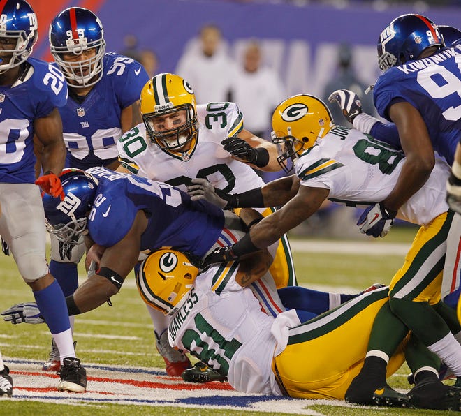 New York Giants middle linebacker Jon Beason (52) picks off a pass and is stopped by Green Bay Packers fullback John Kuhn (30), Green Bay Packers tight end Andrew Quarless (81), and Green Bay Packers wide receiver James Jones (89) during the Packers 27-13 loss to New York during the NFL football game between the Green Bay Packers and New York Giants on November 17, 2013 at MetLife Stadium in New Jersey.