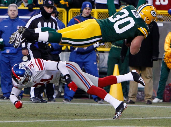 Green Bay Packers fullback John Kuhn dives over New York Giants cornerback Aaron Ross to score a touchdown on an eight-yard pass during the first quarter of their NFC divisional playoff game on January 15, 2012 at Lambeau Field in Green Bay, Wisconsin. The Giants won, 37-20.