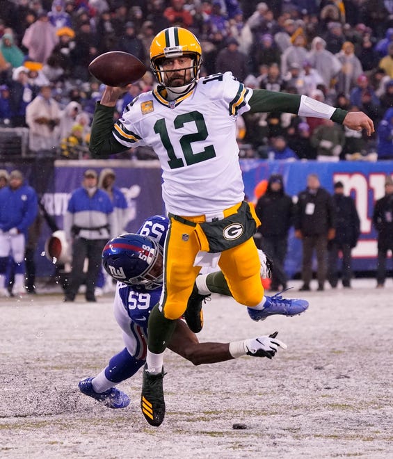 Green Bay Packers quarterback Aaron Rodgers (12) breaks free from the grasp of New York Giants linebacker Lorenzo Carter (59) to throw a fourth quarter TD pass at MetLife Stadium.