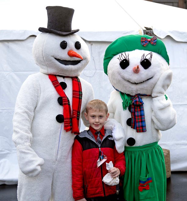 Jacob Martin, 8, poses for a photo with two snow people during the Cocoa with the Clauses event in Cathedral Square Park in Milwaukee, Wis. on Saturday, Dec. 9, 2023.
