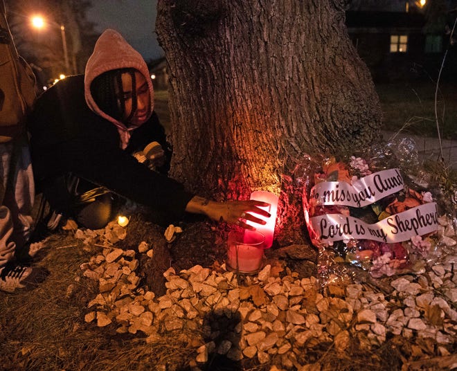 A community member places a candle on a memorial beneath a tree during a vigil on Dec. 9, 2023 honoring the life of Aundre Cross, a 44-year-old U.S. Postal Service worker who was shot and killed while delivering mail a year ago on Dec. 9, 2022 in the 5000 block of North 65th Street in Milwaukee.