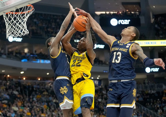 Marquette guard Sean Jones (22) tries to score on Notre Dame guard Markus Burton (3) and forward Tae Davis (13) during the first half of their game Saturday, December 9, 2023 at Fiserv Forum in Milwaukee, Wisconsin.