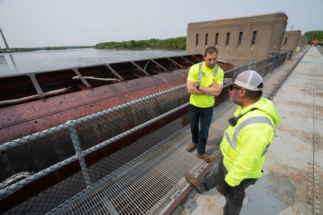 U.S. Army Corps of Engineers employees Aaron Brown and Troy Frank stand near one of the roller gates used to regulate the flow of water Wednesday, May 17, 2023 at Lock and Dam #8 in Genoa, Wis.  The locks allow the boats to gradually adjust to changing river levels. Most towboats can push 15 barges at a time on the river. When those barges reach a 600-foot long lock, they don’t fit. Instead, they have to be split up, which takes more than twice as long.It was constructed and was put into operation by April 1937.
